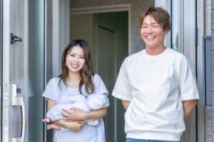 新生児を抱っこする母親と付き添う父親